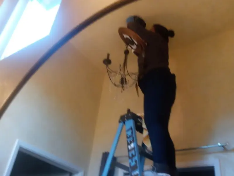 Electrician installing a chandelier in a Fruit Heights residence